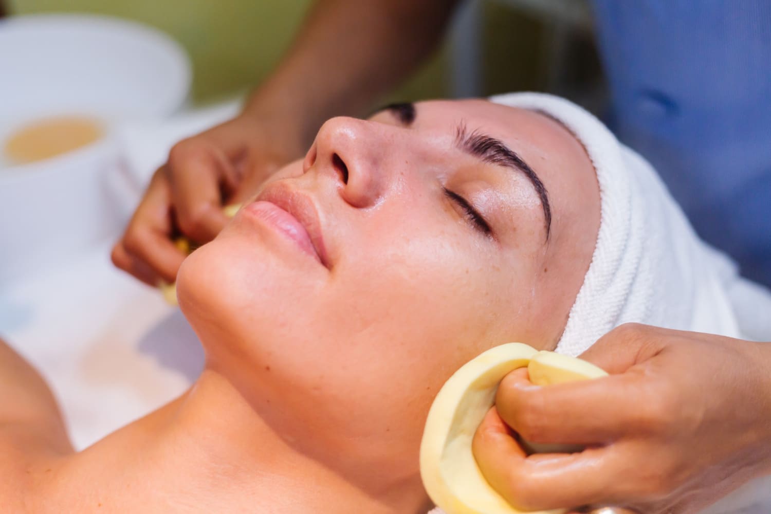 Young woman lying on cosmetologist's table during rejuvenation procedure.<br />
